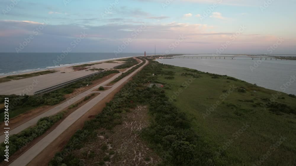 An aerial view of the Robert Moses Water Tower in the far distance, on the southern coast of Long Island, NY. The camera dolly in and boom down over the land during sunrise. An aerial view of the Robert Moses Water Tower in the far distance, on the southern coast of Long Island, NY. The camera dolly in and boom down over the land during sunrise.