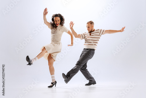 Rhythm and expression. Energetic dance couple in retro style outfits dancing lindy hop, jive isolated on white background. 50s, 60s ,70s american fashion style.