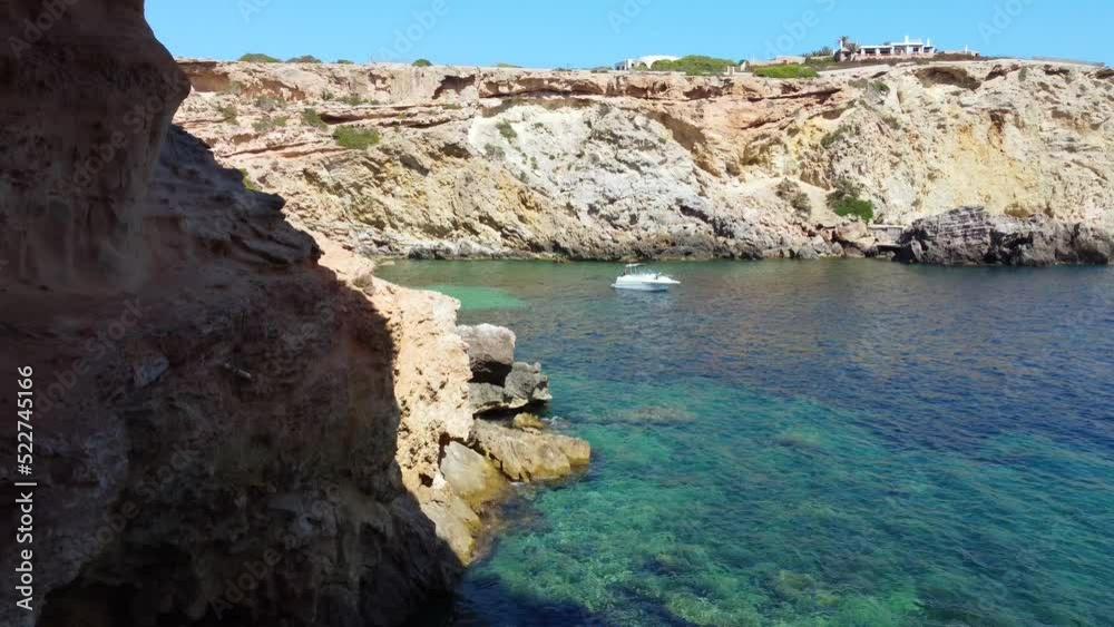 from the sea with motorboats into a cave.
Daring aerial view flight fly backwards drone footage
of cliff edge beach Sa Figuera borda Ibiza summer 2022. 4k Cinematic from above by Philipp Marnitz
