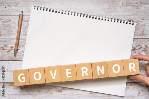 Foto 知事・長官・理事のイメージ｜「GOVERNOR」と書かれたブロック、ノート、ペン、手