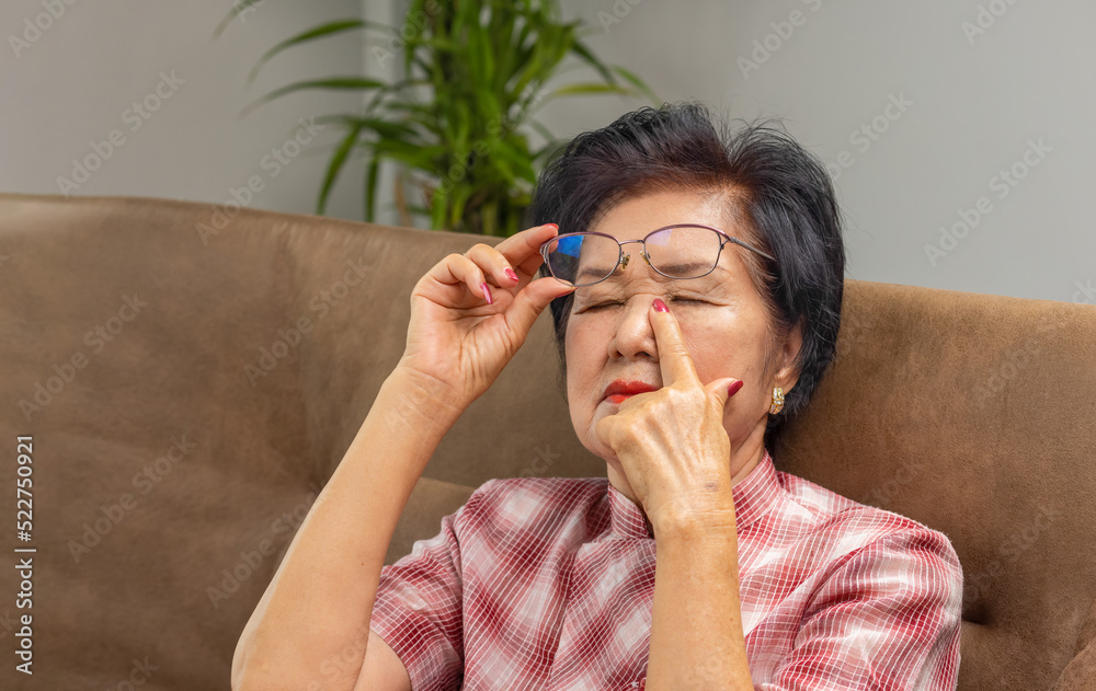 Asian senior older woman taking off glasses, suffering from dry eyes
