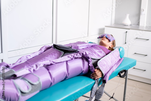 Woman lying with closed eyes during pressotherapy session in beauty clinic. Concept 