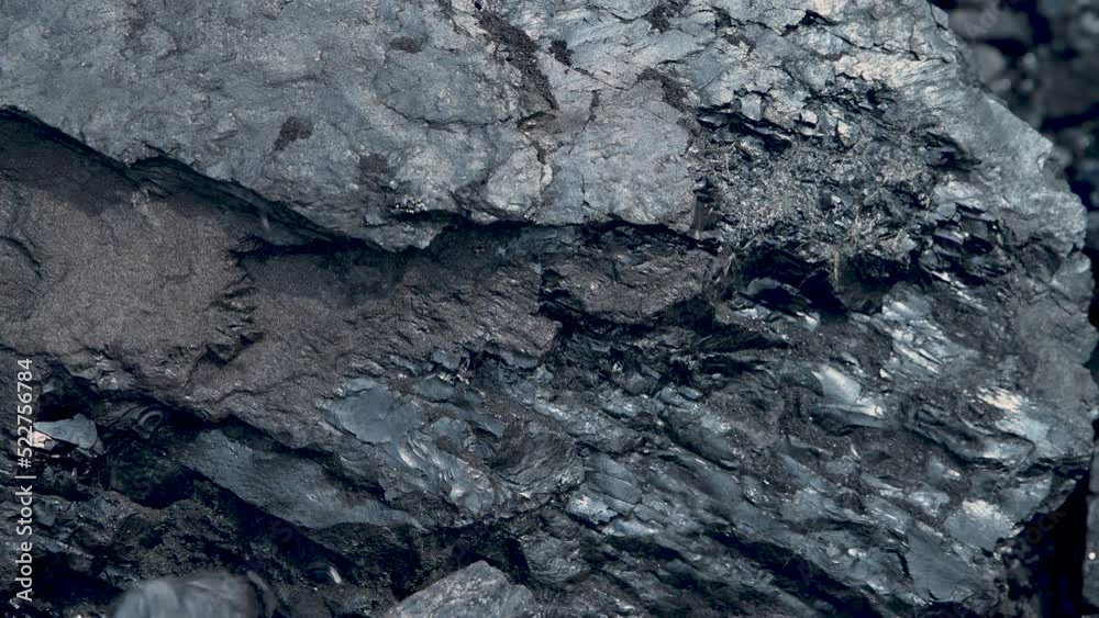 Small stones of coal are pouring against the background of large ones. Energy and fuel industry. Volcanic rock. Small stones of coal are pouring against the background of large ones. Energy and fuel industry. Volcanic rock.