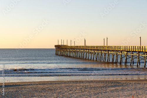 Fototapeta Naklejka Na Ścianę i Meble -  Fishing pier on the Atlantic Ocean at sunrise in Sunset Beach, North Carolina.  Clear sky and calm seas.