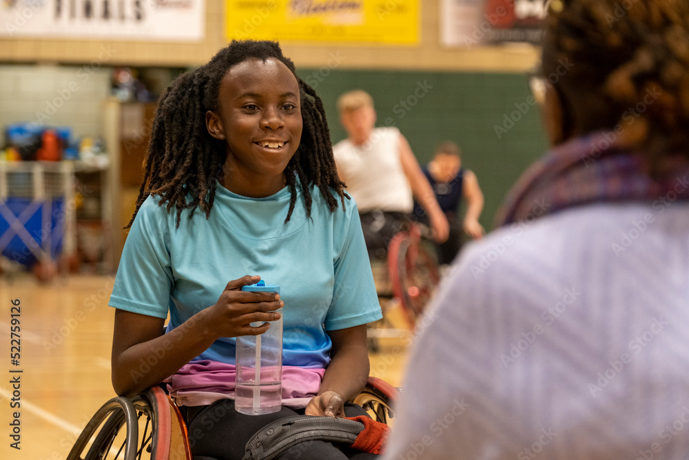 Teenage girl in wheelchair having water break during basketball game Teenage girl in wheelchair having water break during basketball game