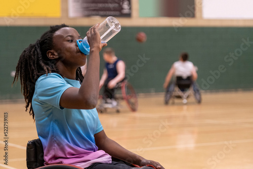 Teenage girl in wheelchair having water break during basketball game