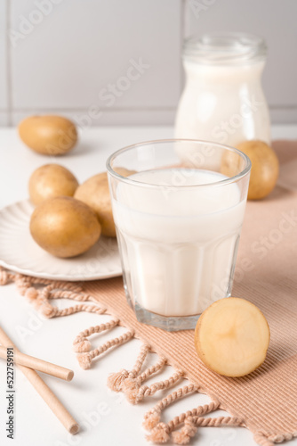 A glass with potato milk on the table with the potato tubers. Vegan trend in healthy eating. Alternative plant milk