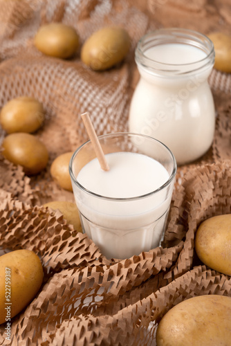 A glass and bottle with potato milk with the potato tubers. Vegan trend in healthy eating. Alternative plant milk