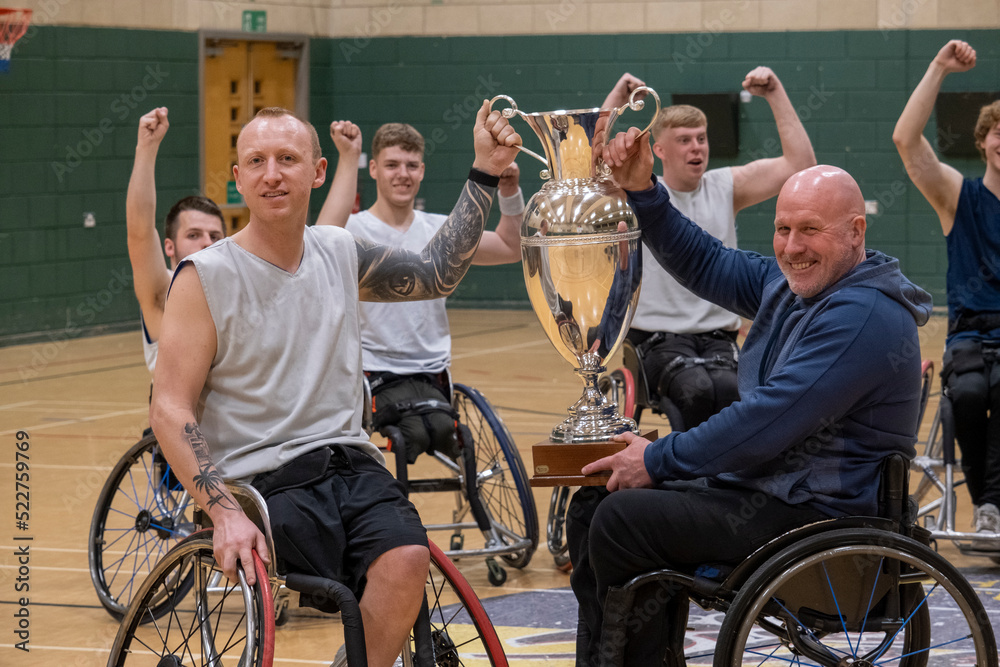 Team of basketball players in wheelchairs with trophy Team of basketball players in wheelchairs with trophy