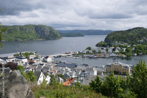 Farsund, Norway - May 30, 2022: Panoramic view of the city and many islands from a hill in a sunny spring day. A spectacular view to Lyngdalsfjorden and town suburbs. Trees, sunny day. Selective focus
