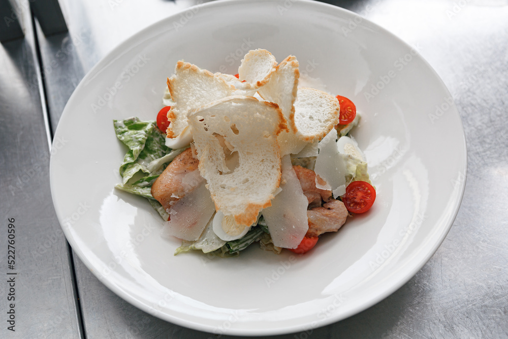 Caesar salad with roasted chicken breast, croutons, cherry tomatoes and parmesan on white plate Caesar salad with roasted chicken breast, croutons, cherry tomatoes and parmesan on white plate