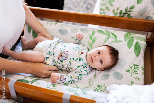 Mum getting new baby dressed on changeable smiling at camera photo