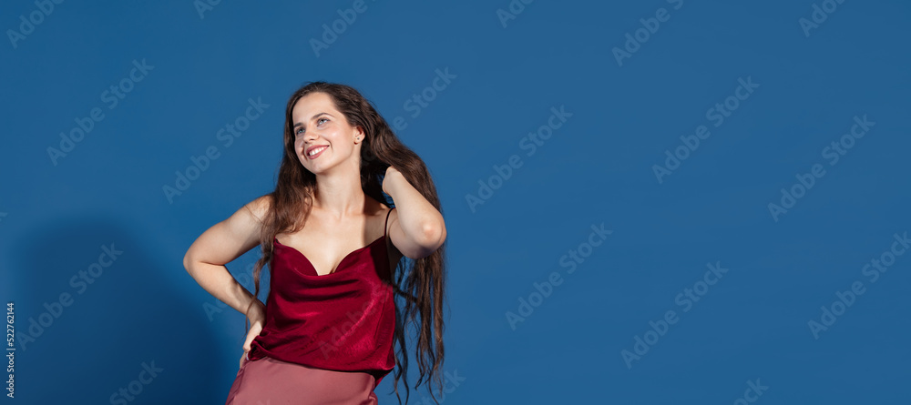 Portrait of young beautiful woman with long brown hair posing in stylish clothes isolated over blue studio background Portrait of young beautiful woman with long brown hair posing in stylish clothes isolated over blue studio background