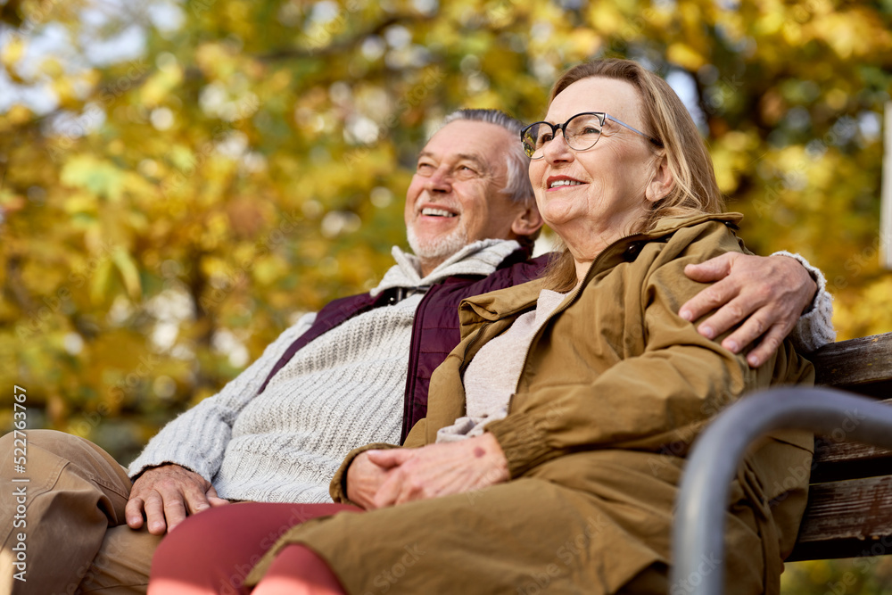 Fototapeta premium Senior caucasian couple sitting at the bench in park