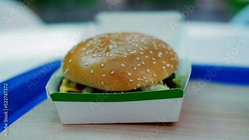 Close-up of an appetizing hamburger in a box on the table in the food court.