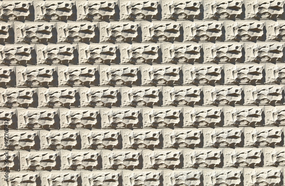 Gray concrete wall with decorative rectangle forms in shape of rocks carved on the surface. Background and texture. Gray concrete wall with decorative rectangle forms in shape of rocks carved on the surface. Background and texture.
