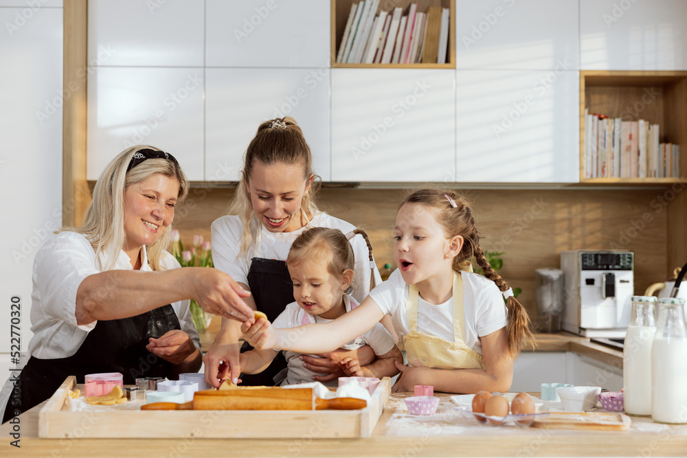 Christmas time. Family spending time in modern light kitchen preparing cookies for baking. Grandmother and young mother teaching offsprings baking cooking christmas cookies biscuits preparing surprise Christmas time. Family spending time in modern light kitchen preparing cookies for baking. Grandmother and young mother teaching offsprings baking cooking christmas cookies biscuits preparing surprise