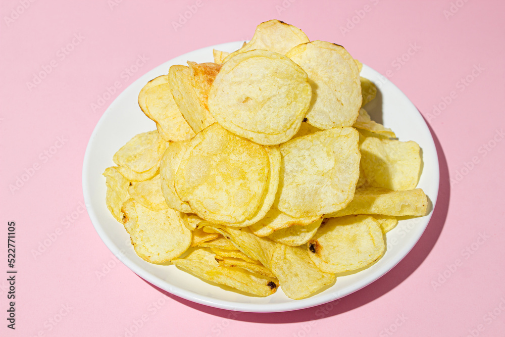 A plate of chips on a pink background. A delicious way to cook potatoes. Delicious fast food A plate of chips on a pink background. A delicious way to cook potatoes. Delicious fast food