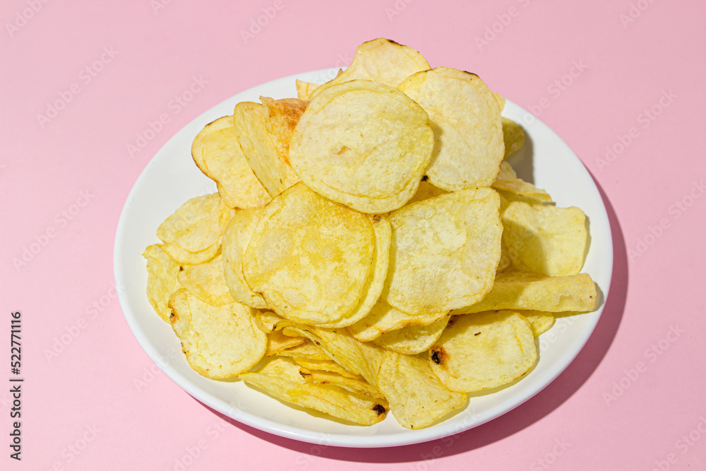 A plate of chips on a pink background. A delicious way to cook potatoes. Delicious fast food A plate of chips on a pink background. A delicious way to cook potatoes. Delicious fast food
