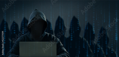 Dangerous anonymous hackers are using laptops for identity theft, internet, cybercrime. Cyber attack, destruction and malware concept. Blackout. Digital binary code on background.