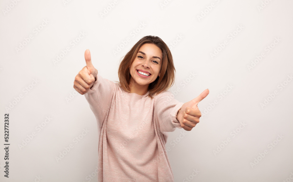 Delighted young lady smiling and showing like sign in studio Delighted young lady smiling and showing like sign in studio