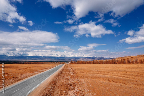 Beautiful landscape road in autumn forest with snow peaks mountains Chuysky tract, Altai Kurai steppe Russia