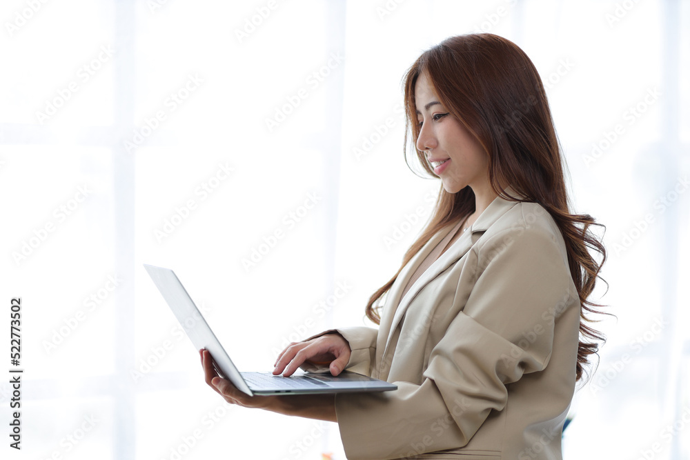 Portrait of a charming Asian businesswoman standing with a laptop. Portrait of a charming Asian businesswoman standing with a laptop.