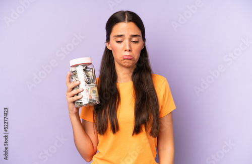 pretty hispanic woman feeling sad and whiney with an unhappy look and crying. dollar banknotes savings photo