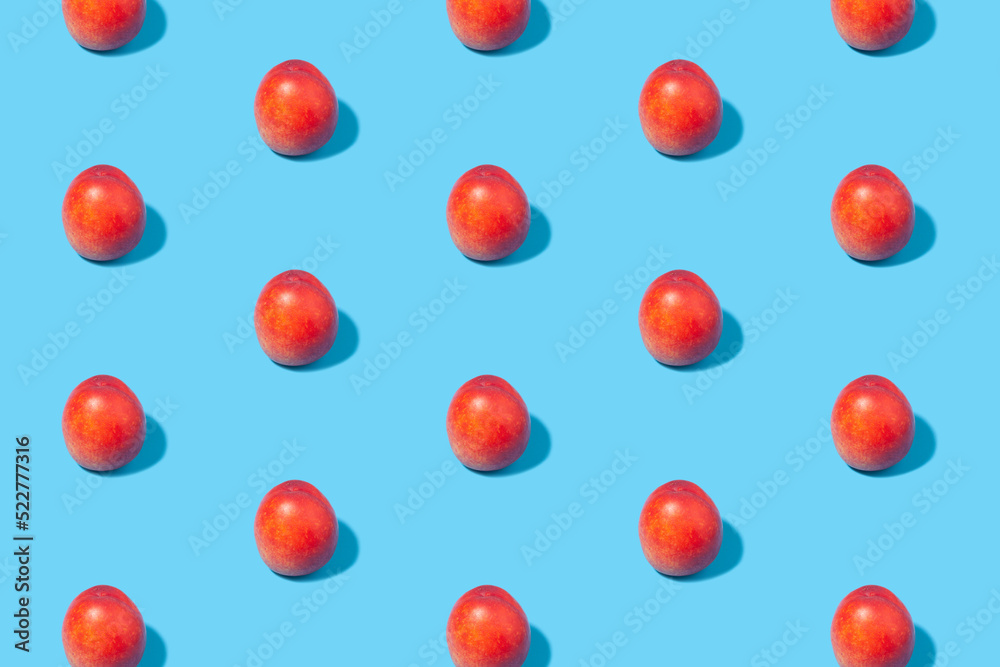 Ripe nectarines are laid out in even rows on a blue background.
