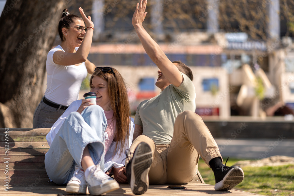 Front view of three students sitting and talking in an university campus Front view of three students sitting and talking in an university campus