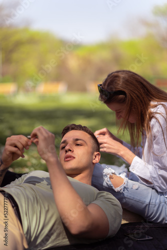 Two friends lying down in a park and laughing. Close up of couple lying down outdoors enjoying the warm sun