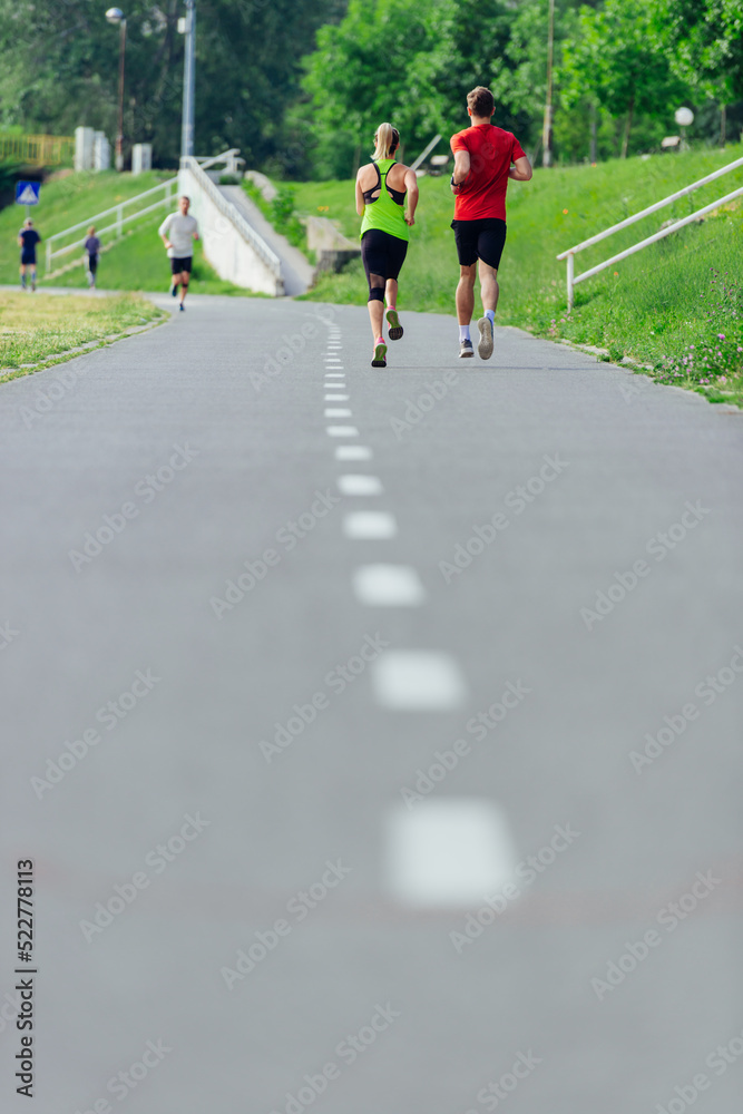 Rearview of caucasian female and male running outdoors on a road