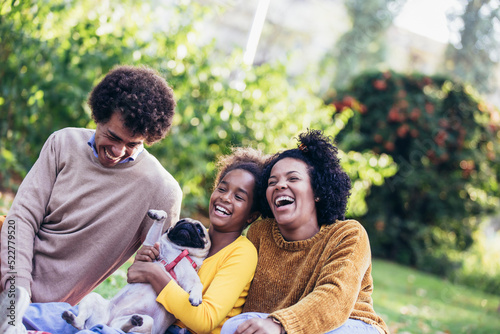 Beautiful young family lying on a picnic blanket with their dog, enjoying an autumn day in park photo