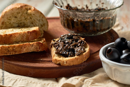 Φωτογραφία Black Olive Tapenade in bowl with spoon and Bread.
