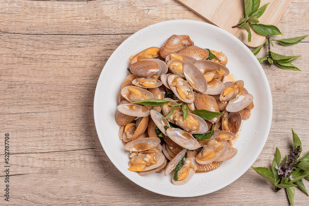 Stir fried clams with basil leaves in a white bowl