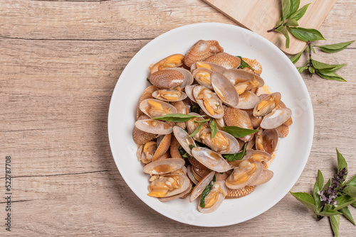 Stir fried clams with basil leaves in a white bowl