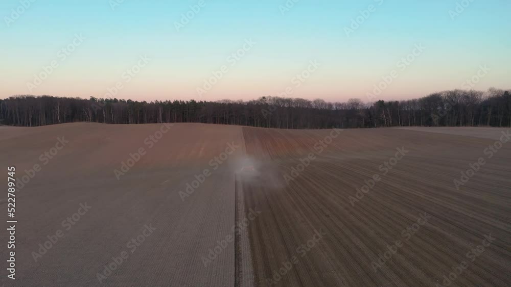 Tractor working on agricultural plantation at sunset Tractor working on agricultural plantation at sunset