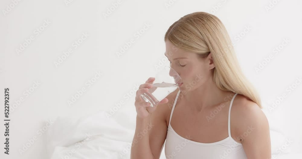 Beautiful lady holding glass of mineral water, hydrating her body in the morning Beautiful lady holding glass of mineral water, hydrating her body in the morning