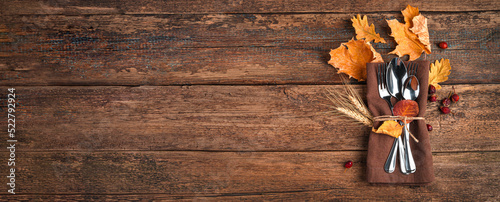 Napkin, cutlery and autumn leaves on a wooden background with space to copy. The concept of Thanksgiving, Halloween