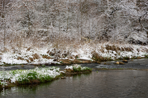 Bielsko-Biała, dopływ Wisły, wczesna wiosna, brzeg rzeki odbijający się w wodzie, śnieg, drzewa, woda, trawa. 
