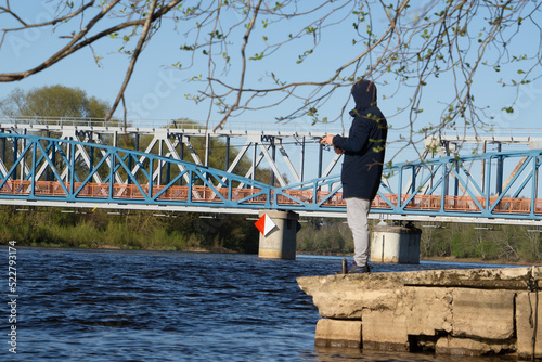 Fisherman Gatis is fishing in lake near bridge photo