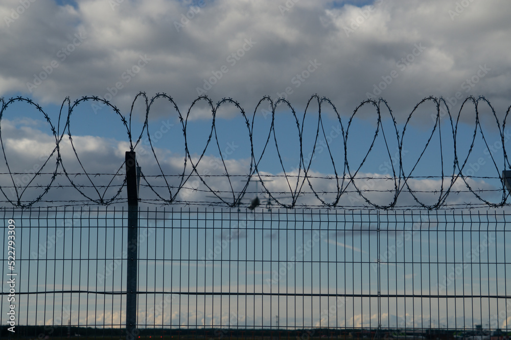 Danger zone with Barbed wire and Airplane in the sky that is Landing Danger zone with Barbed wire and Airplane in the sky that is Landing