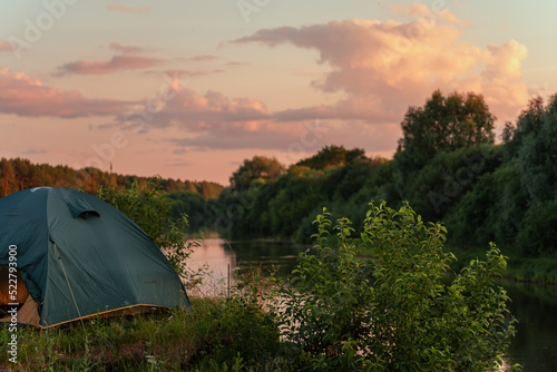 A tent on the river bank against the background of an evening summer sunset.