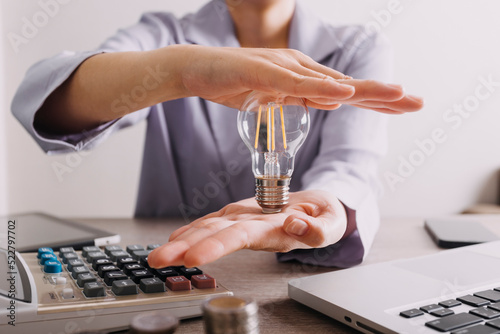 Energy saving light bulb with stacks of coins and shopping cart for saving  financial and shopping concept.