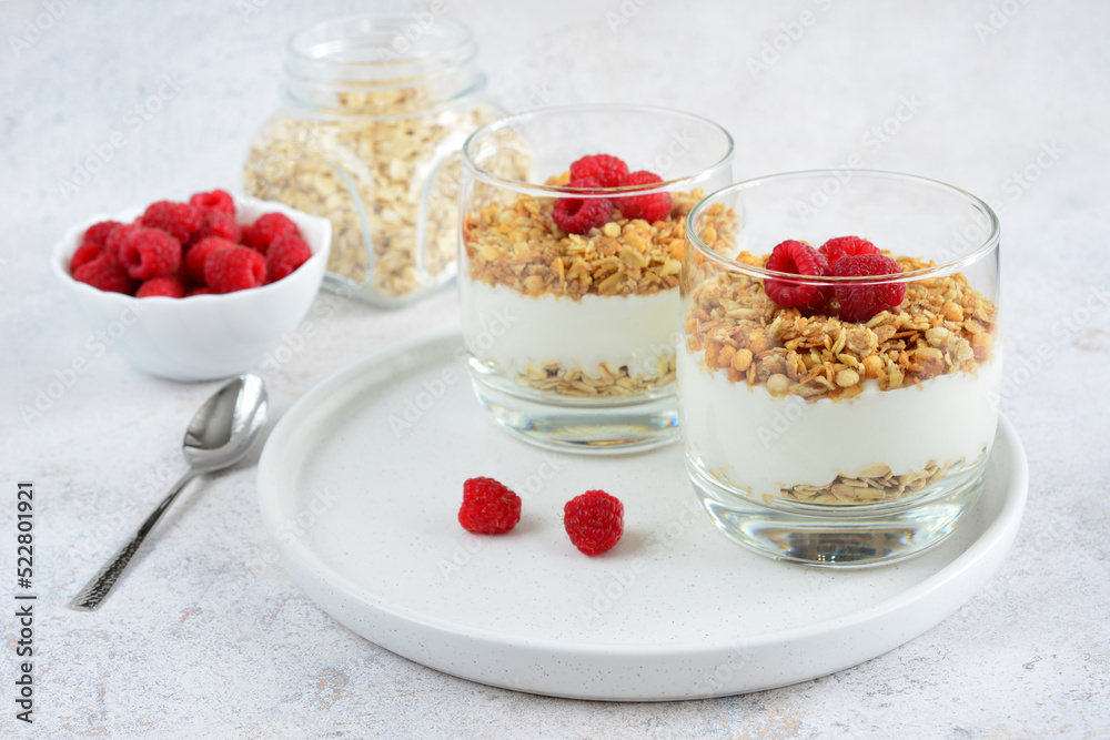 muesli with yoghurt and raspberry in drinking glasses on white tray, close-up muesli with yoghurt and raspberry in drinking glasses on white tray, close-up