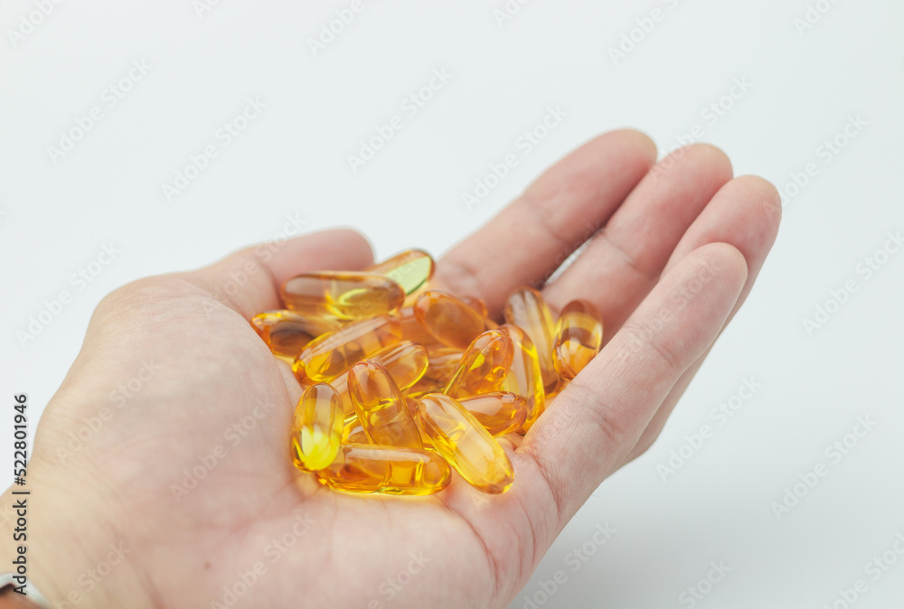 close-up view tablet of fish-oil supplement in man hand on white background close-up view tablet of fish-oil supplement in man hand on white background