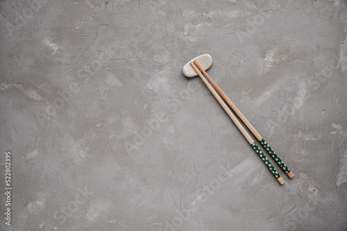 Wooden chopsticks and chopstick rest on a gray background. Top view. Copy space