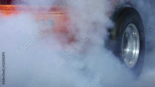 Car wheel spinning wheel and smoking, Race car burning tire for warm up tire before competition, Racing car burns rubber preparation for race on speed track.
