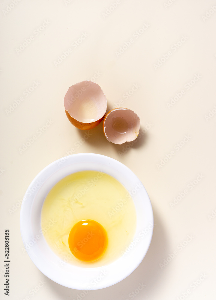 Raw eggs and egg shell in a glass bowl on the table. Top View. Broken White Background. Raw eggs and egg shell in a glass bowl on the table. Top View. Broken White Background.