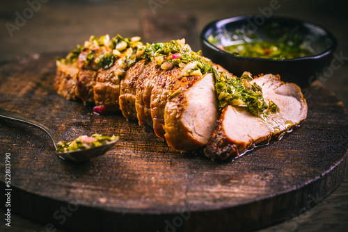 Quadro su tela Homemade grilled pork steak with chimichurri verde sauce on cutting board on dar